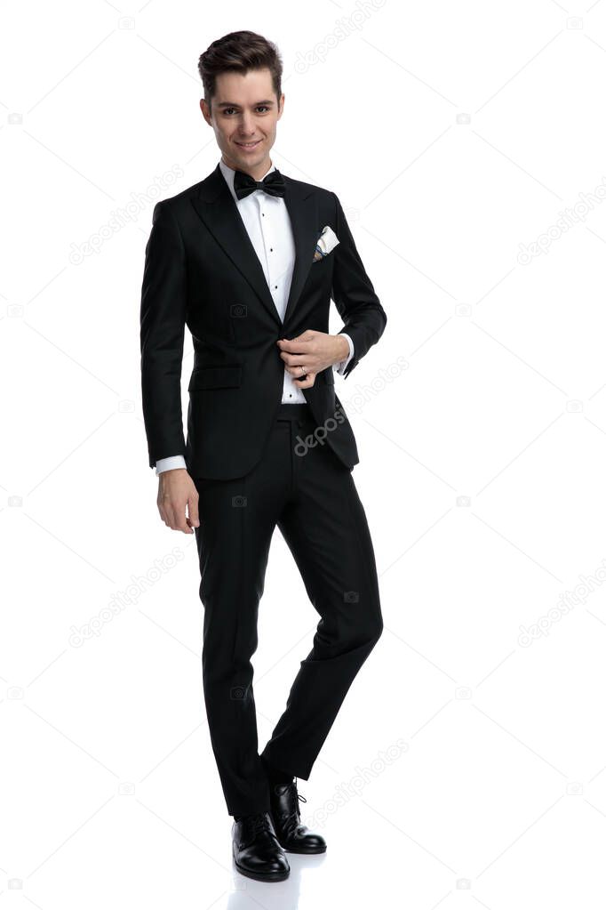 happy young man arranging coat and walking on white background