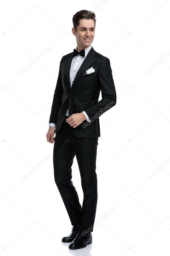 happy young groom in tuxedo looking to side