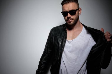 Ciddi görünümlü dramatik bir adam ceketini düzeltip çekiyor.