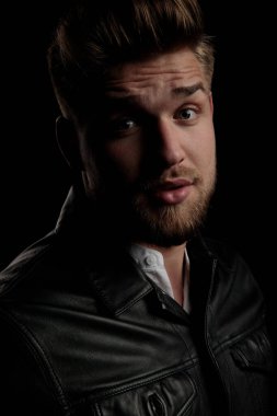 Deri ceketli sıradan bir adam kameraya bakıyor.