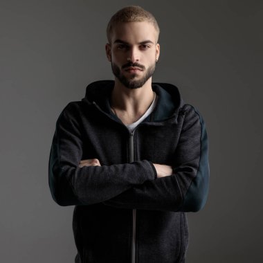 casual man standing with crossed arms and staring at camera