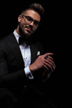 İş adamı kameraya bakarken yüzüğünü düzeltiyor.