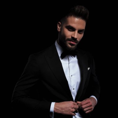 Siyah smokin giyen işadamı dikilip ceketini açıyor.