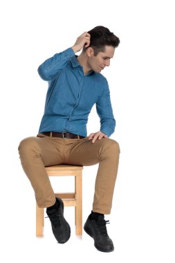 Akıllı, sıradan bir adam aşağı bakıyor ve kafasını kaşıyor.