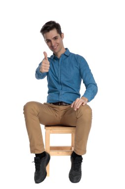 Mutlu genç adam gülümsüyor ve baş parmak işareti yapıyor.