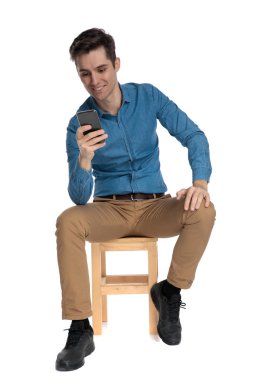 Mutlu genç adam gülümsüyor ve telefonu tutuyor.