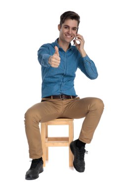 Mutlu genç adam telefonda konuşuyor ve baş parmak işareti yapıyor.