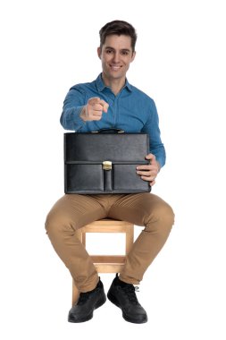 Mutlu sıradan bir adam bavulu tutar ve işaret eder.