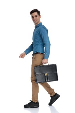 Gülümseyen ve bavulu tutan genç adamın yan görüntüsü