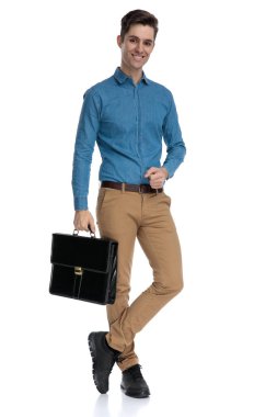 Mavi tişörtlü akıllı adam gülümsüyor ve bavulu tutuyor.