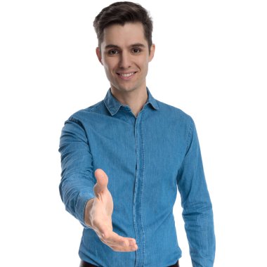 Mavi gömlekli mutlu genç adam gülümsüyor ve el sıkışıyor.