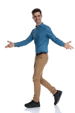 Mavi gömlekli mutlu genç adam gülümsüyor ve sunuyor 