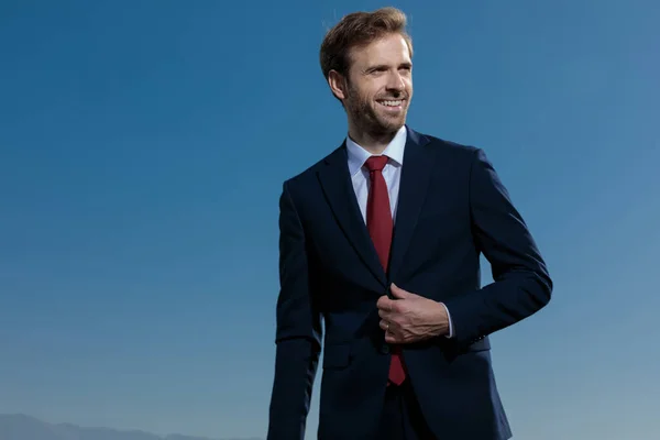 Hombre de negocios alegre ajustando su chaqueta y riendo — Foto de Stock