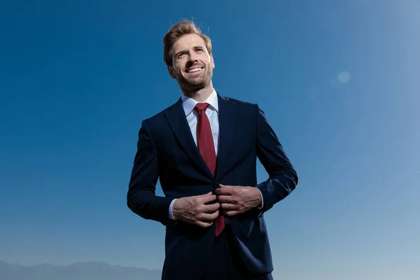 Cheerful businessman adjusting his jacket and laughing — Stock Photo, Image