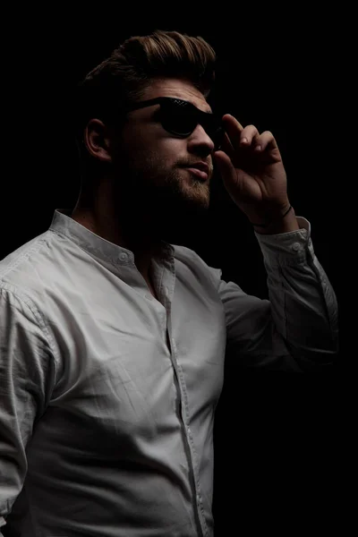 Homem vestindo camisa branca de pé e fixando óculos de sol — Fotografia de Stock