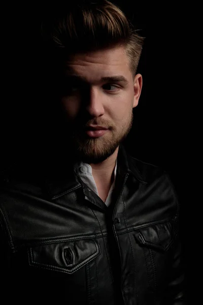 Casual man wearing black leather jacket looking away curious — Stock Photo, Image