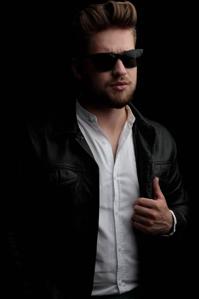 Man wearing sunglasses standing and looking away while fixing ja — Stock Photo, Image
