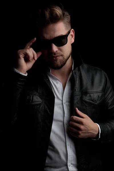 Casual man standing and fixing his sunglasses and jacket — Stock Photo, Image