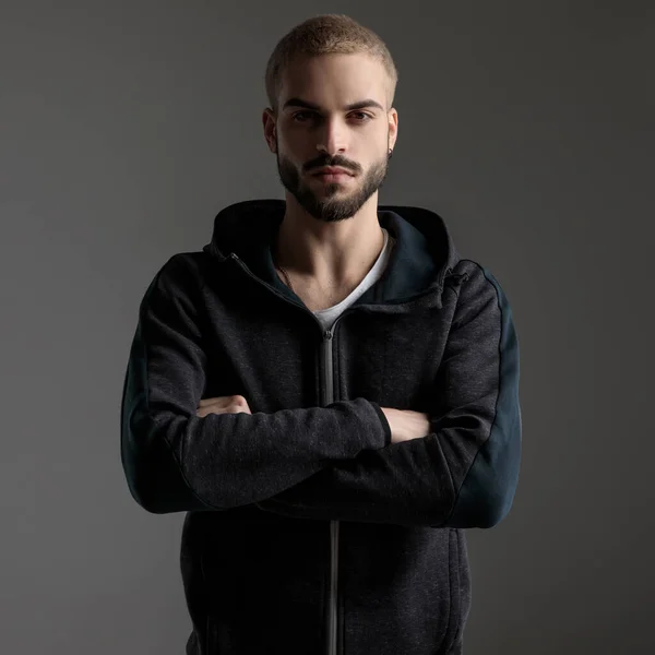 Casual man standing with crossed arms and staring at camera — Stockfoto