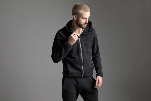 Casual man standing and fixing his tracksuit while looking aside — Stock Photo, Image