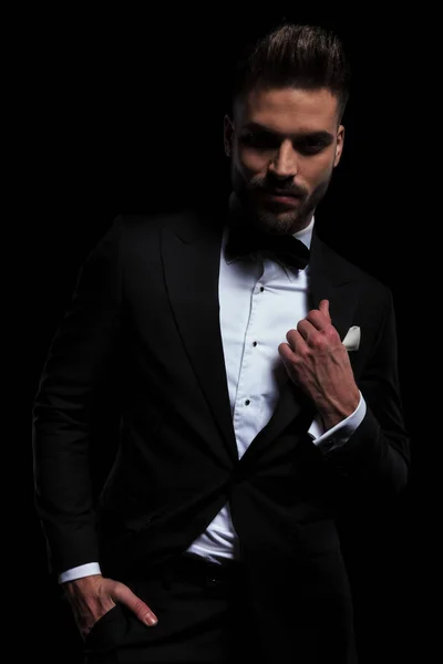 Businessman wearing black tuxedo and fixing his lapel — Stock Photo, Image