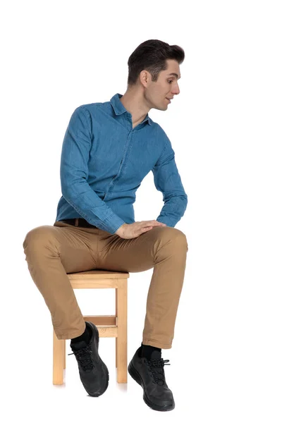 Nieuwsgierige jongeman in blauw shirt probeert te kijken naar kant — Stockfoto