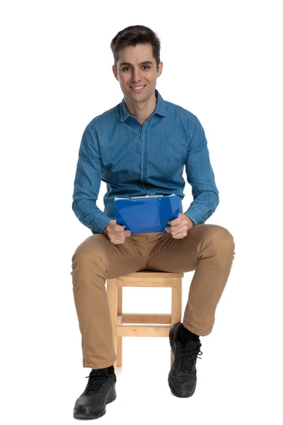 Щасливий молодий чоловік у блакитній сорочці посміхається і тримає кишеню — стокове фото