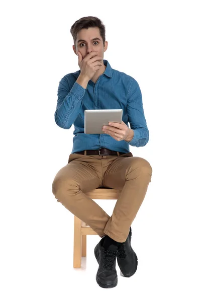 Shocked young man covering mouth and holding tab — Stock Photo, Image