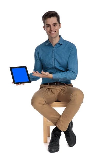 Happy young man smiling and presenting tab to side — Stock Photo, Image