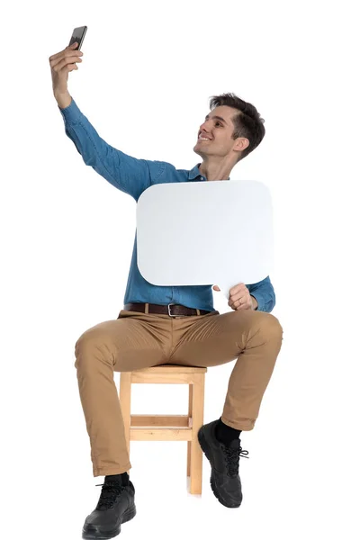 Happy young man holding speech bubble and taking selfie — Stock Photo, Image