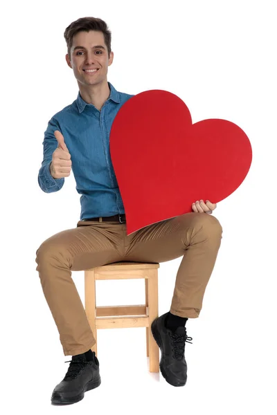 Inteligentní ležérní muž drží červené srdce a dělá palce nahoru znamení — Stock fotografie