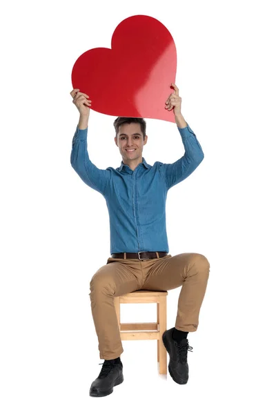 Homem casual inteligente segurando o coração vermelho e sorrindo — Fotografia de Stock