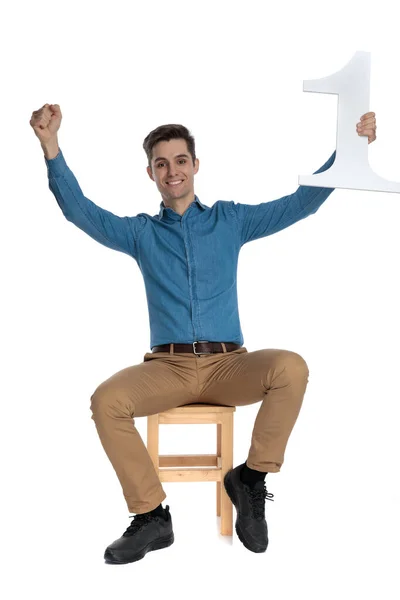 Joven feliz sosteniendo el cartel número uno y celebrando la victoria —  Fotos de Stock