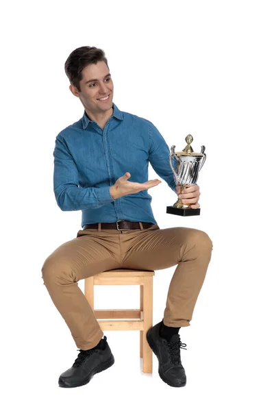 Heureux jeune homme présentant trophée et sourire — Photo