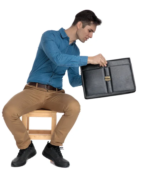 Nieuwsgierige jonge man op zoek en op zoek naar koffer — Stockfoto