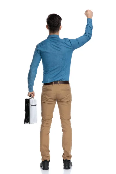 Back view of young man holding suitcase and celebrating victory — Stockfoto