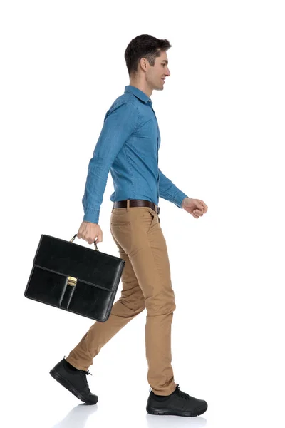 Vue latérale du jeune homme tenant une valise et marchant — Photo