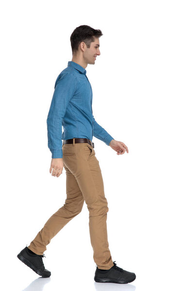side view of smart casual man smiling and walking