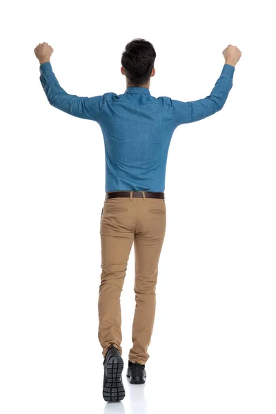 Terug uitzicht van opgewonden jonge man lopen met armen in de lucht — Stockfoto
