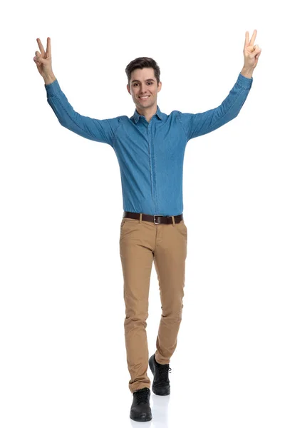 Glücklicher junger Mann geht und macht Friedenszeichen — Stockfoto