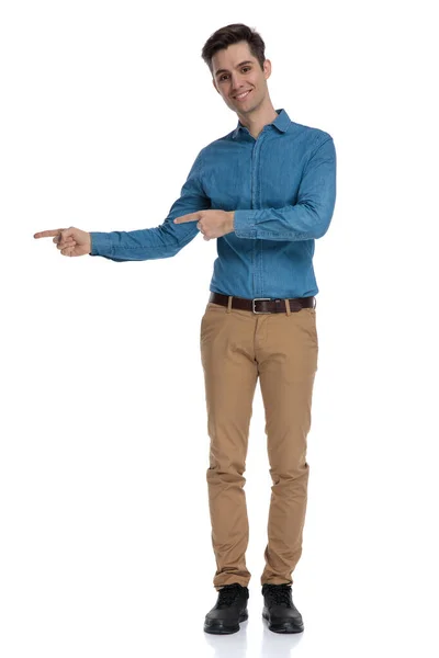 Boldog fiatal férfi kék ingben, ujjal mutogatva — Stock Fotó