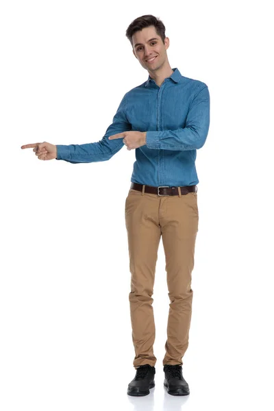 Feliz joven con camisa azul apuntando de un lado a otro — Foto de Stock