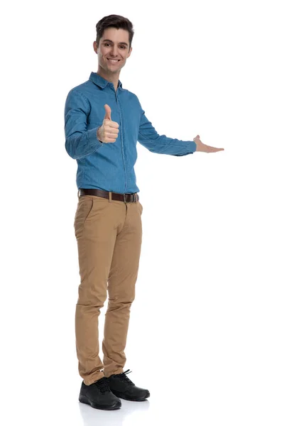Fiatal elegáns férfi teszi hüvelykujját fel jel és bemutató oldalra — Stock Fotó
