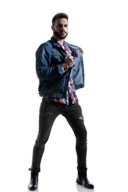 esrarengiz moda adamı kot ceket tutuyor ve çekiyor.