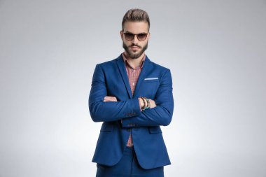 Güneş gözlüğü takıp kollarını kavuşturan havalı bir manken.