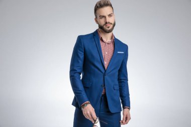 Mavi takım elbiseli, elinde güneş gözlüğü olan dramatik havalı adam.