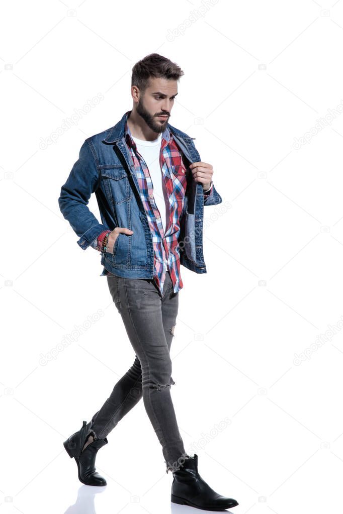 sexy fashion man in plaid shirt holding jeans jacket and walking