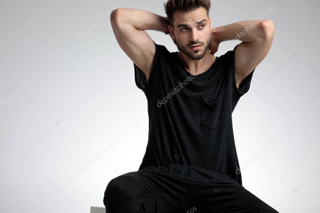 sexy fashion guy holding hands behind neck and posing