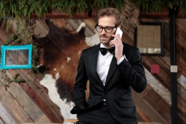 Genç damat telefonla konuşuyor, gözlük takıyor.