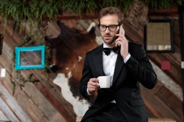 Endişeli damat elinde bir bardak ile telefonuyla konuşuyor.